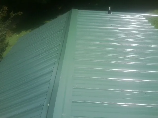 New green metal panels meeting at the ridge of a roof — Flat Roof Repair work by our crew in Edison