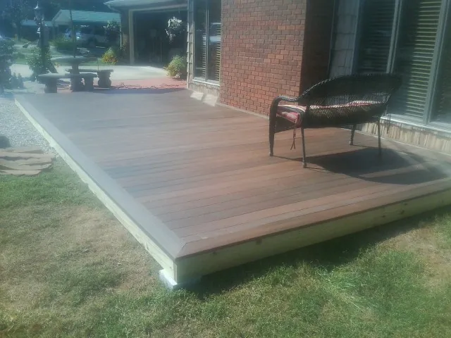 New wood deck and wicker chair beside a brick house in Edison