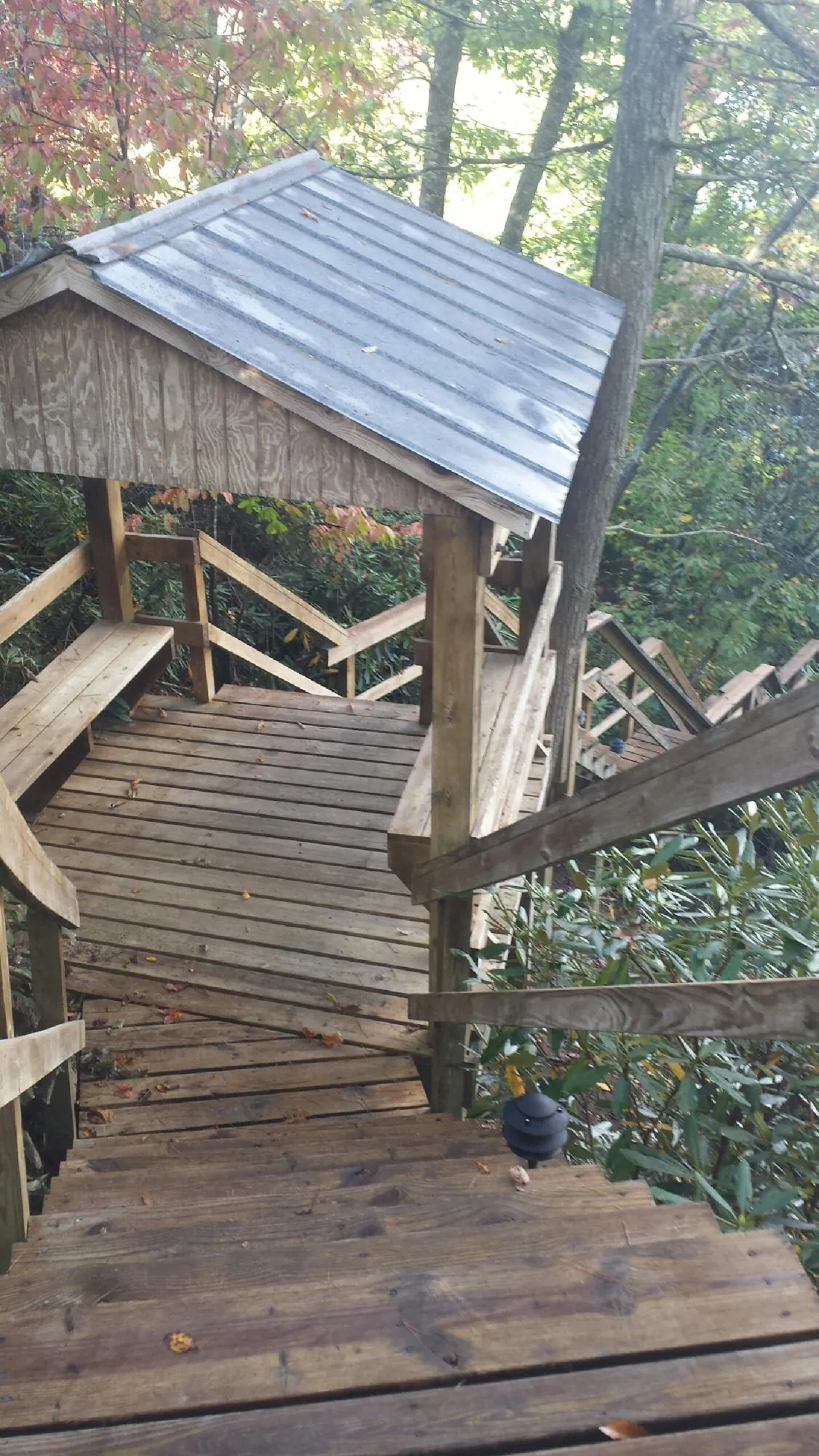 Metal roofed shelter over wooden steps on a wooded walkway — Skylight Repair & Installation work by our crew in Edison