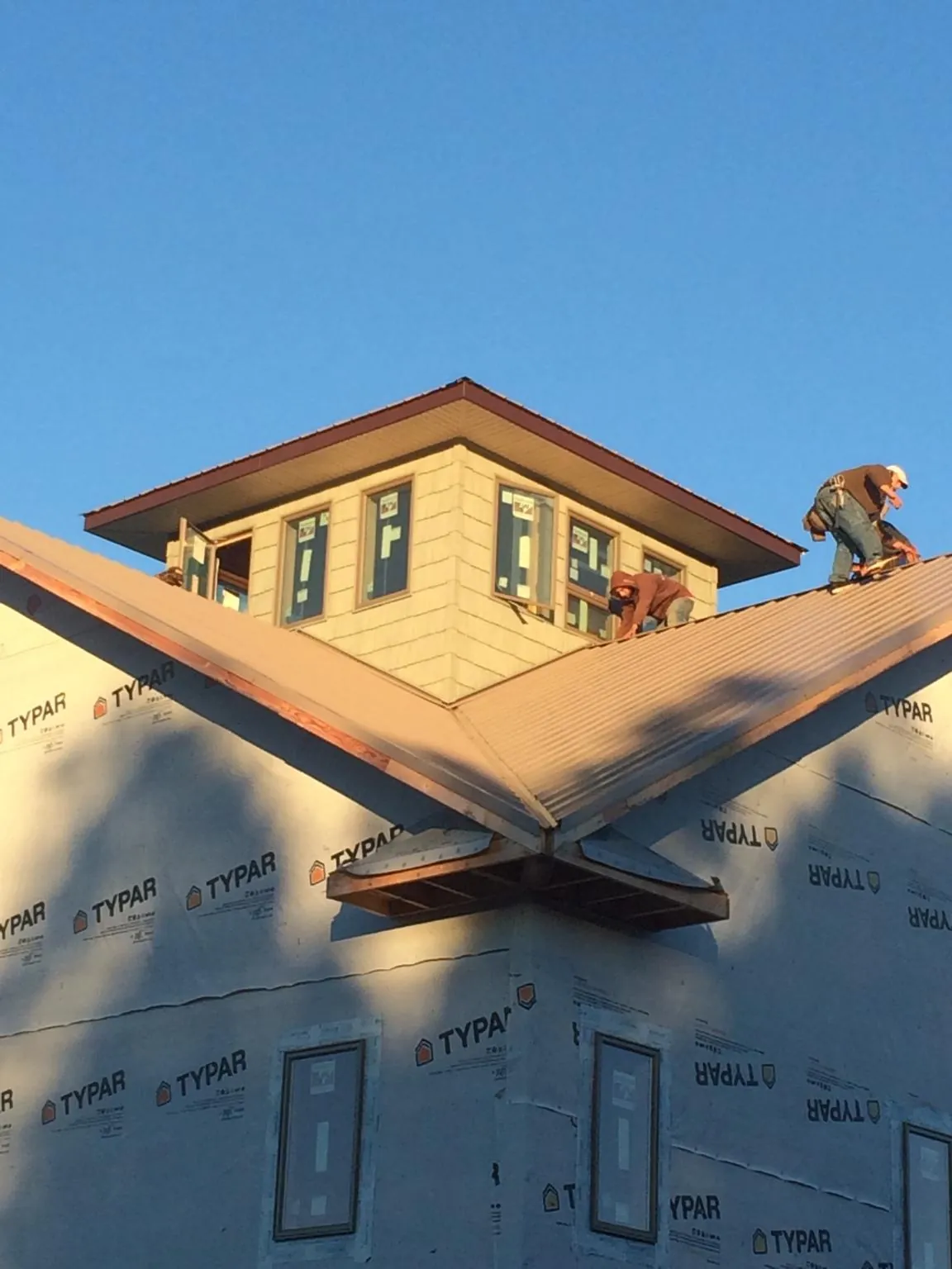 Roofers working around a rooftop cupola on a new metal roof at sunset — Roof Waterproofing in Edison by Roofing Brothers